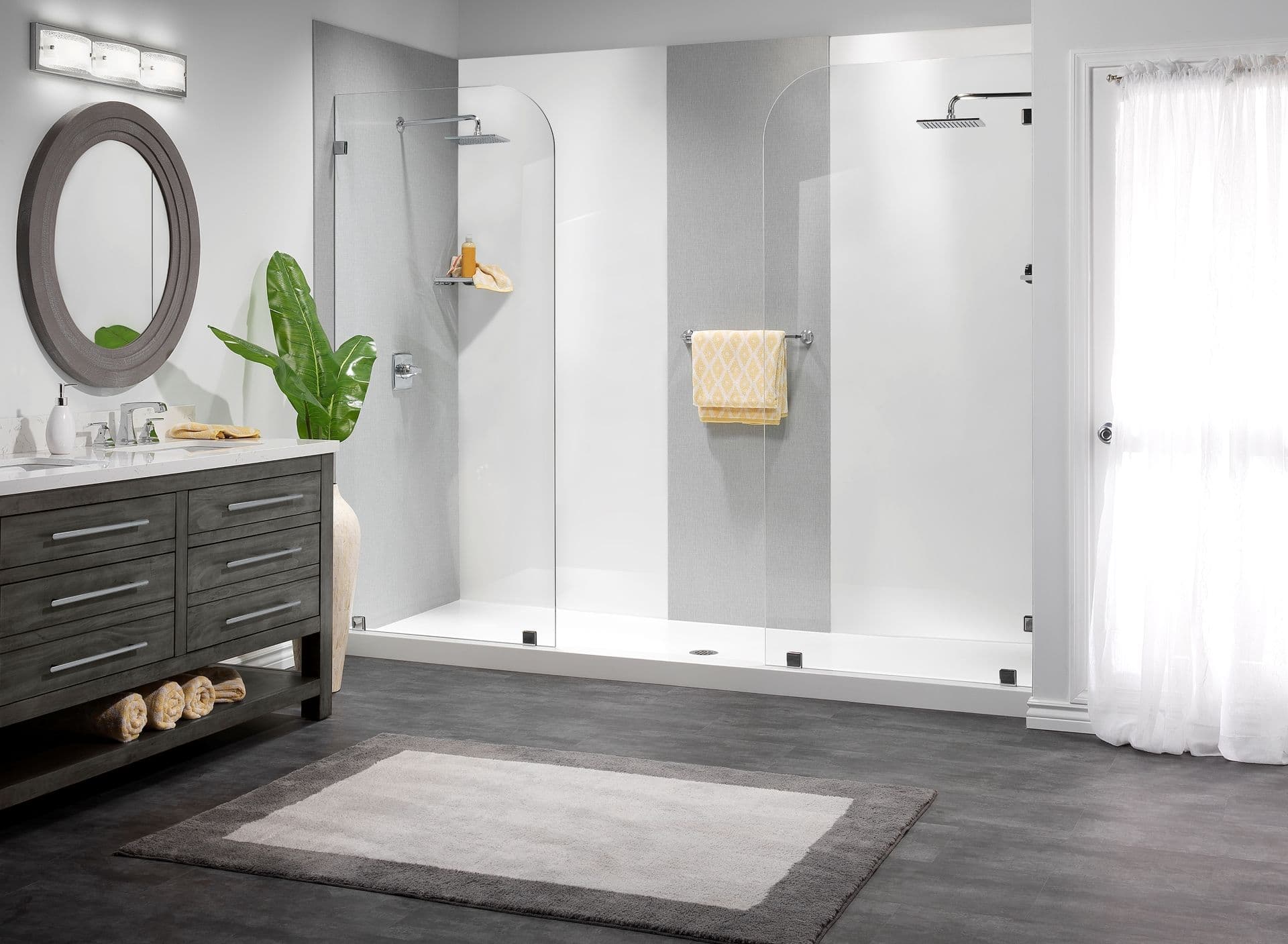 A double walk-in shower with rainfall shower heads, glass partitions, and gray and white walls.
