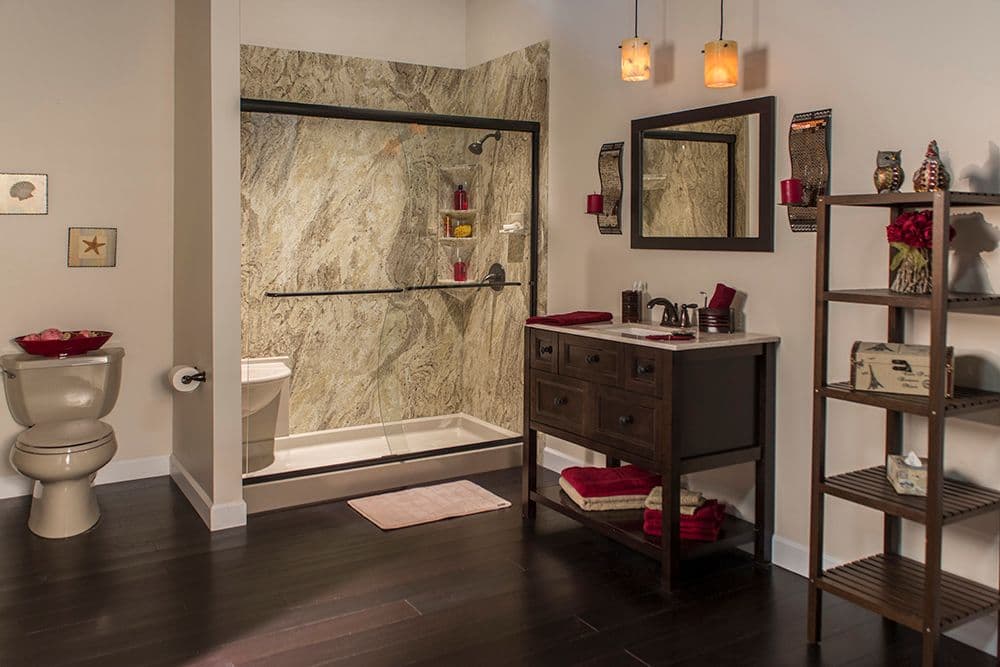 A beige bathroom with brown and red accents, a walk-in shower with sliding glass doors, built-in bench, and brown marble patterned walls.