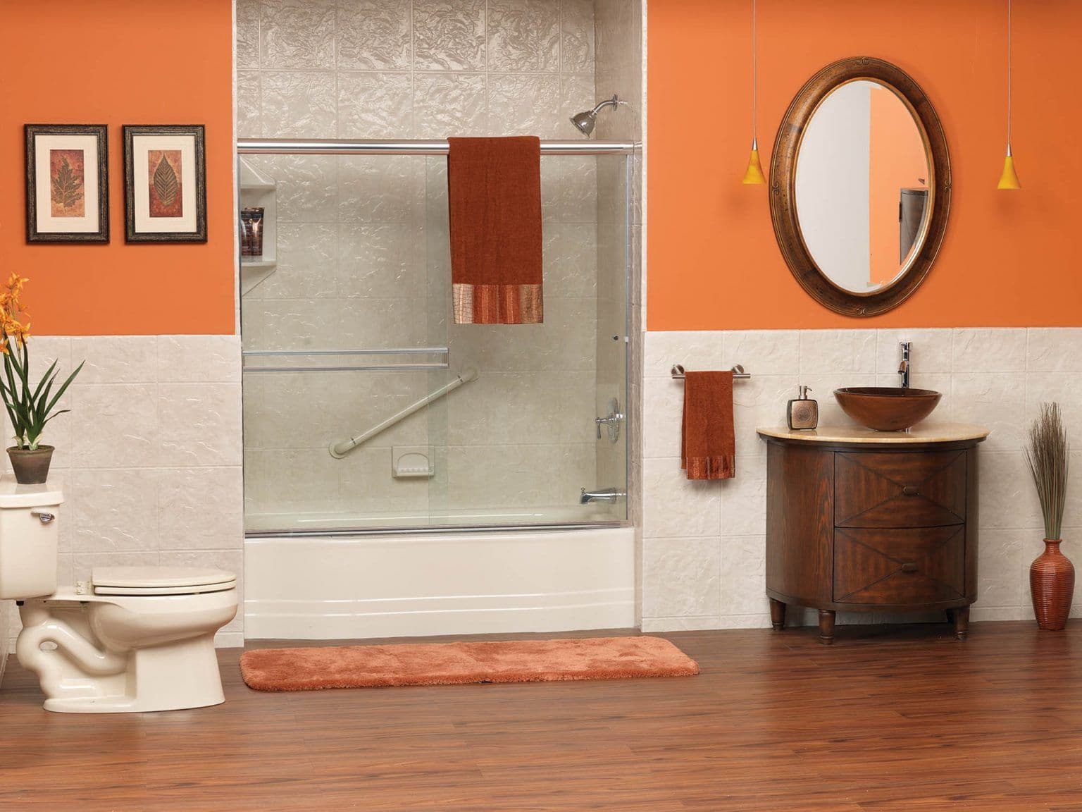 An orange and white bathroom with a combination shower tub with sliding glass doors, textured walls, and diagonal grab bar.