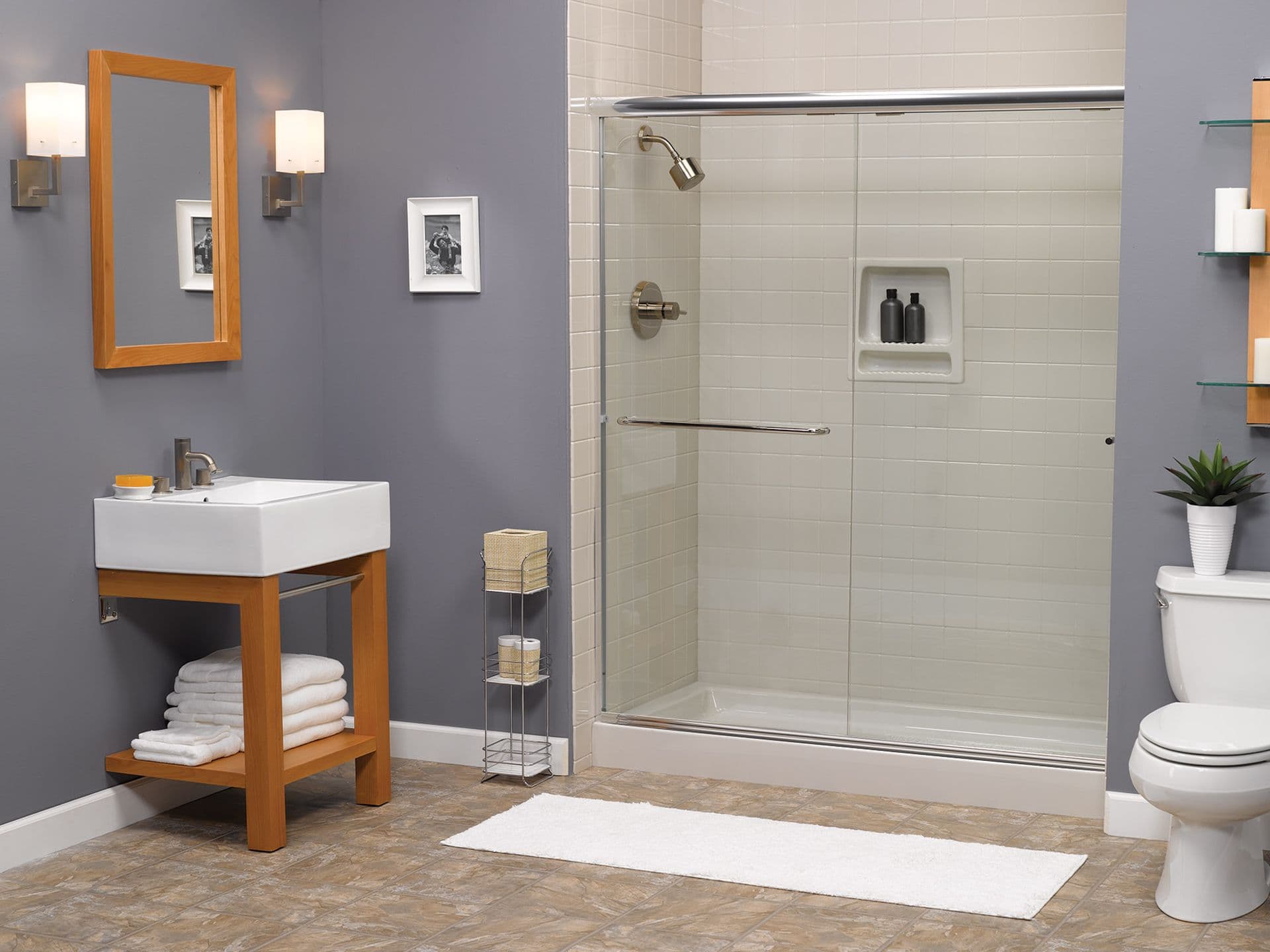 A gray bathroom with a walk-in shower with sliding glass doors and built-in storage caddy.