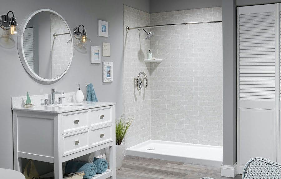 A light gray bathroom with a walk-in shower with light-gray tile-patterned walls.