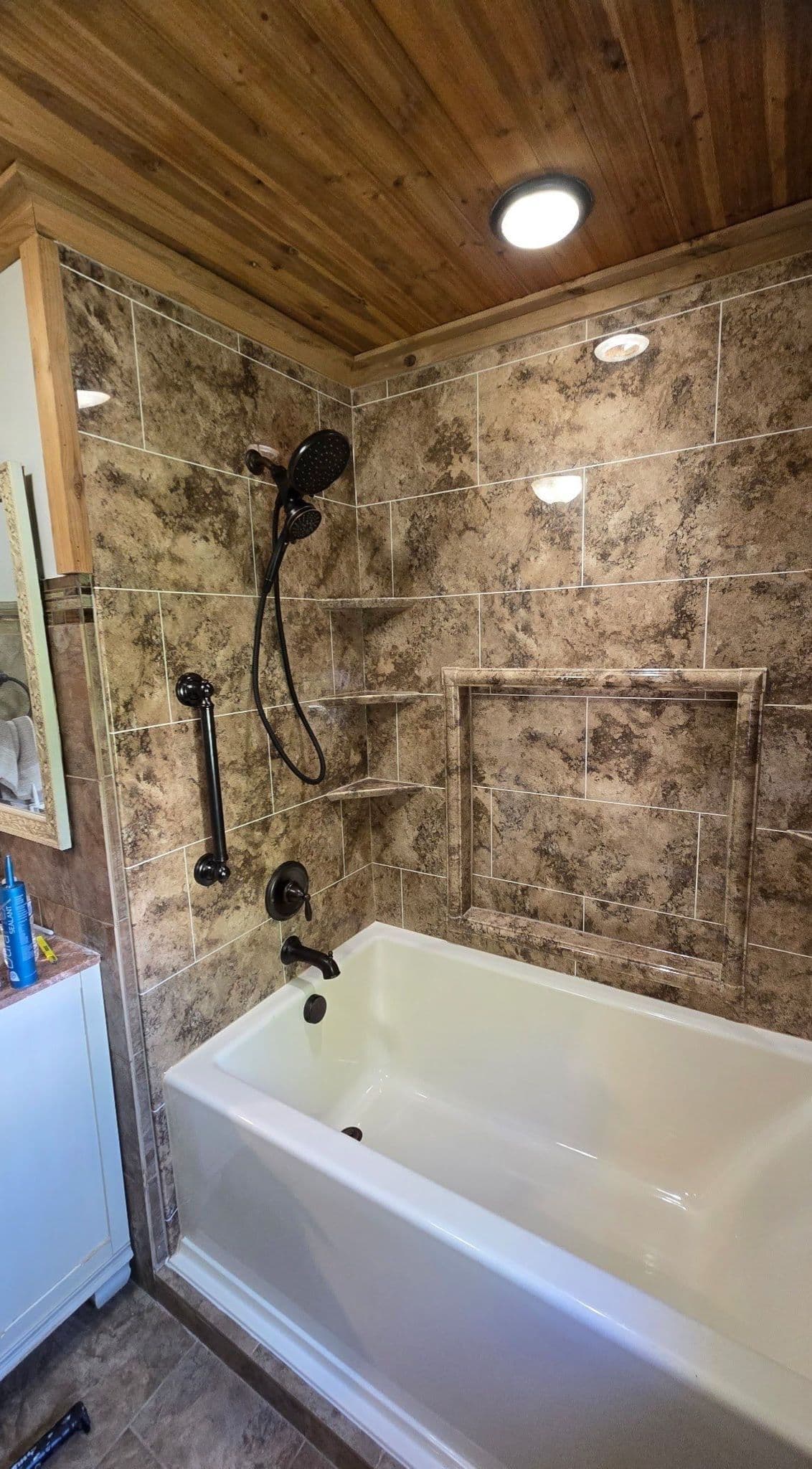 A combination shower tub with brown textured wall, storage caddy, and black fixtures.