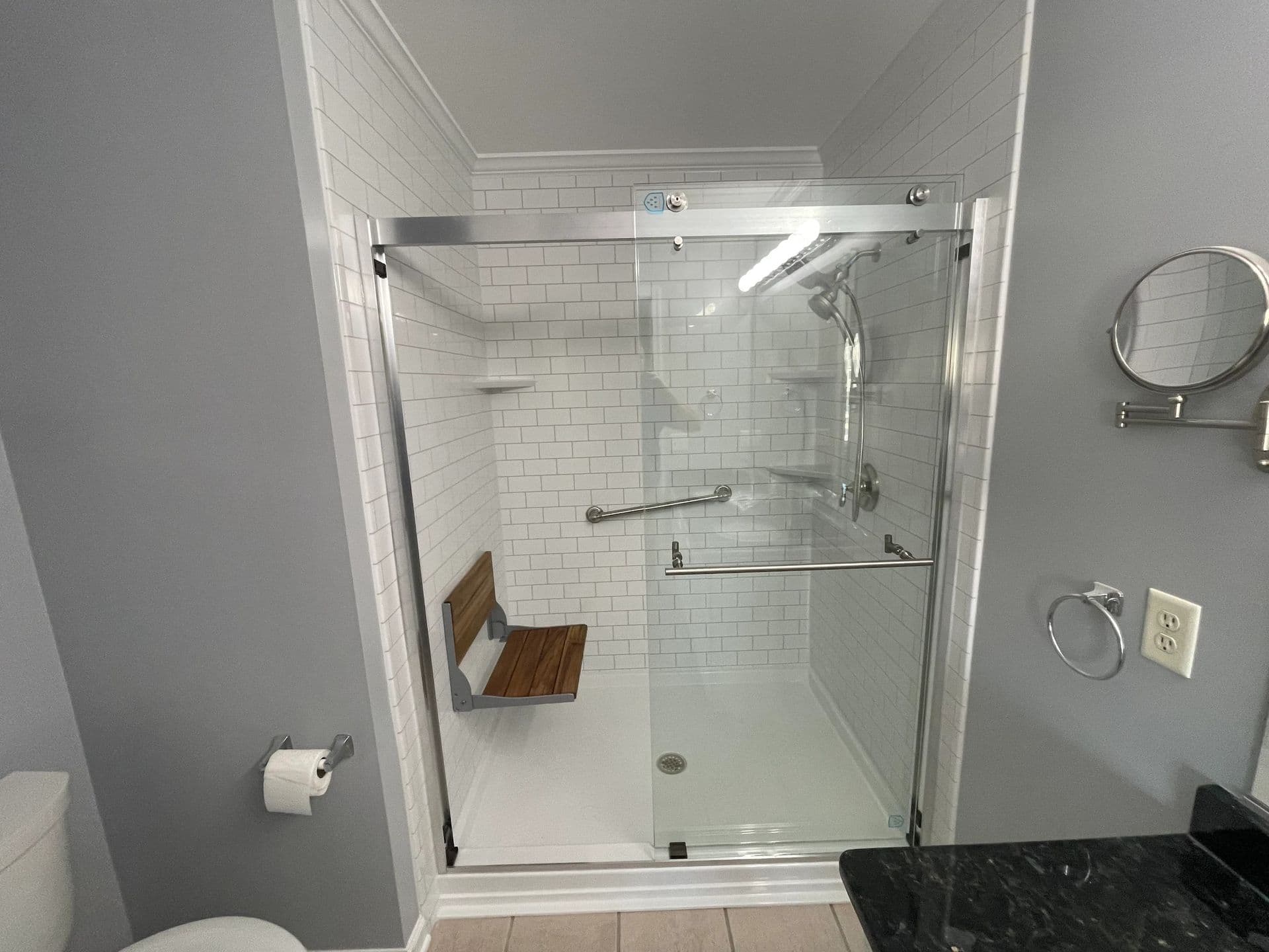 A converted walk-in shower with a built-in bench and sliding glass doors.