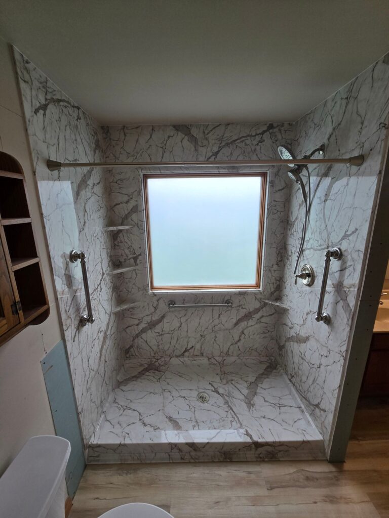 Tub to shower conversion featuring a new marble look shower and large window.